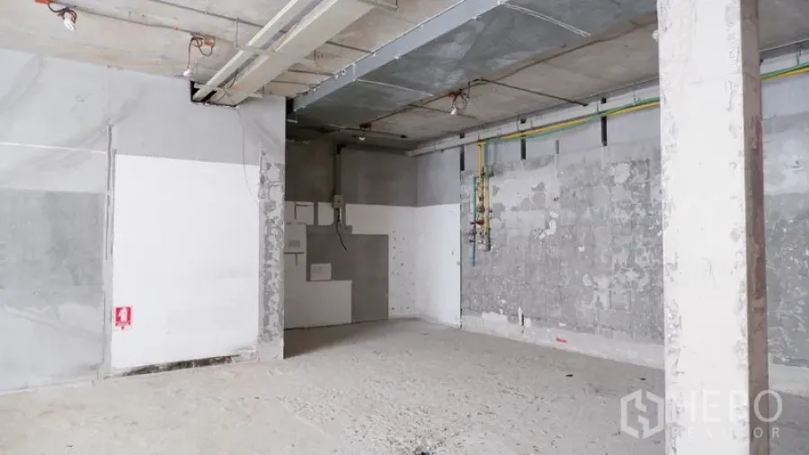 零售空间 出租在Watthana, Bangkok - 店铺一角，天花管线、混凝土柱与粗糙找平地面。