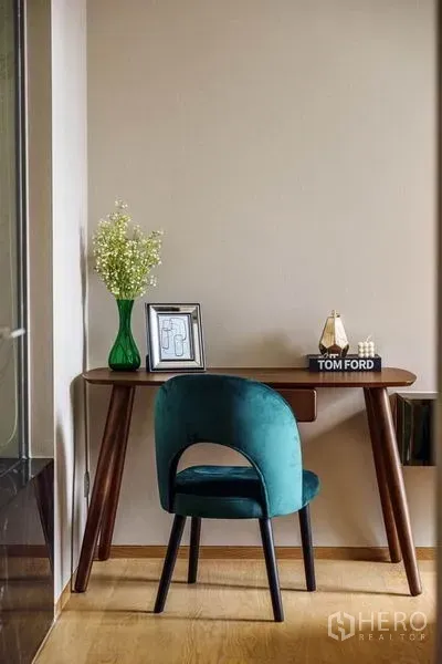 公寓 出租或出售在Bang Rak, Bangkok - 紧凑工作区，木质书桌、墨绿色椅与花瓶装饰。