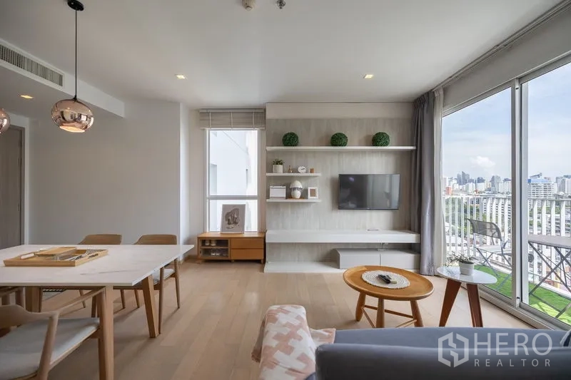 Condominium for rent in Watthana, Bangkok - Floating shelves with decor and flat-screen TV in a bright living space.