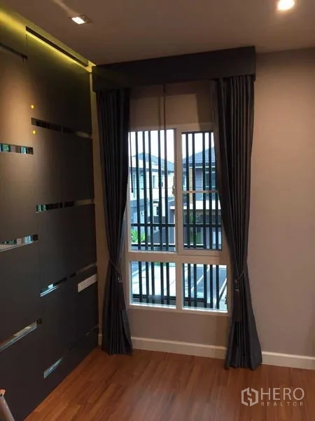 Townhouse for sale in Bang Khae, Bangkok - Small nook with a window dressed in dark curtains beside a feature wall.
