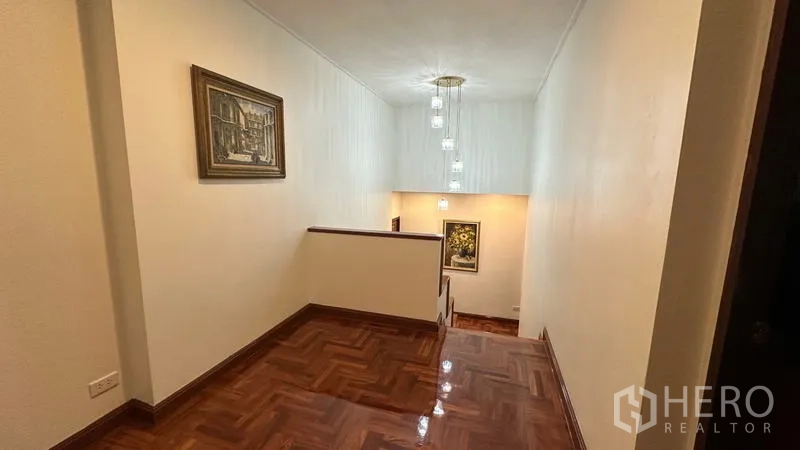 独立式住宅 出租在Watthana, Bangkok - 二层走廊，亮面木地板与吊灯。