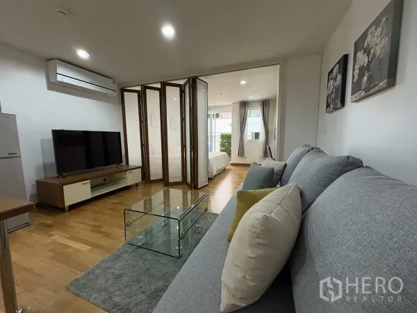 公寓 出租在Khlong Toei, Bangkok - 客厅带电视柜，折叠门打开通向采光充足的卧室。