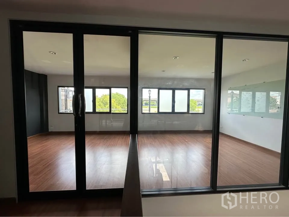 Townhouse for rent in Pak Kret, Nonthaburi - Two glass-enclosed rooms with wide windows overlooking greenery.
