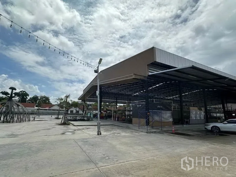 Warehouse for rent in Sai Noi, Nonthaburi - Front angle of covered warehouse structure with ample forecourt and lighting poles.