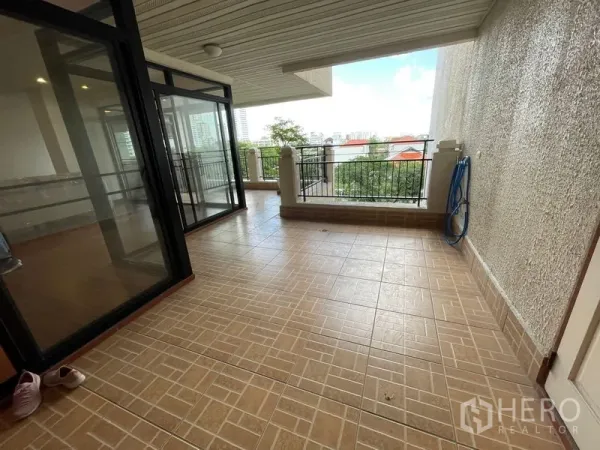 Condominium for rent in Watthana, Bangkok - Large covered balcony with tiled floor, railing and open city views accessed via sliding glass doors.