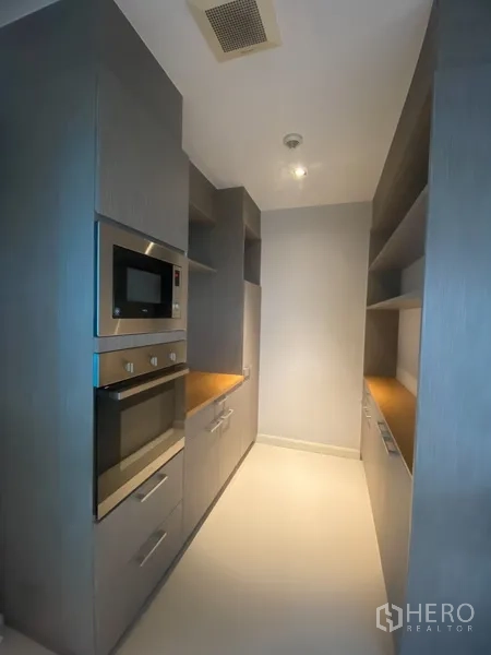 Apartment for rent in Pathum Wan, Bangkok - Compact galley pantry with built-in oven, microwave and storage cabinets.