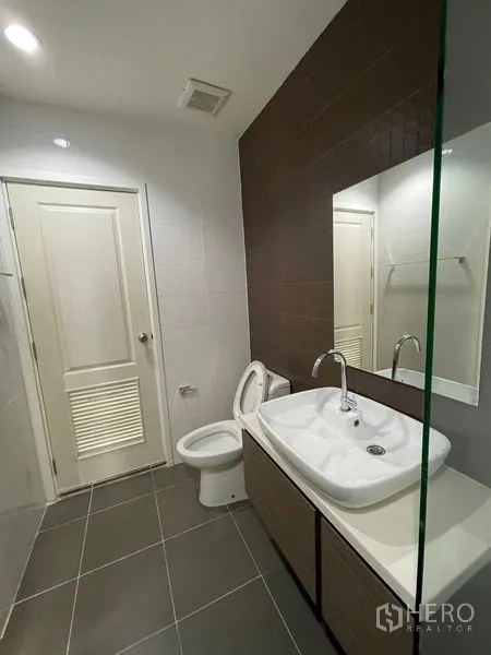 Townhouse for rent in Bang Kapi, Bangkok - Modern bathroom with large vanity, mirror, toilet and gray floor tiles.