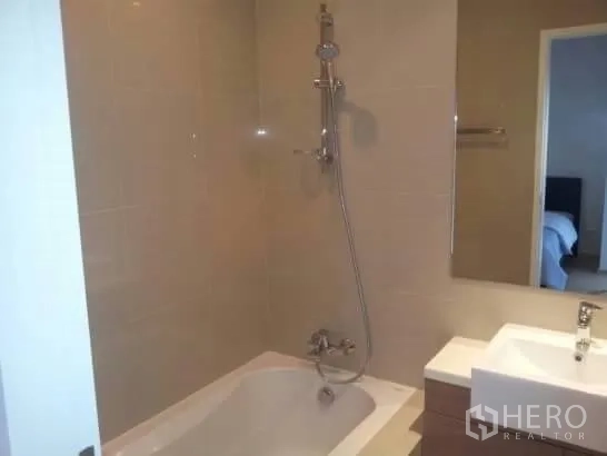 Condominium for rent in Watthana, Bangkok - Modern bathroom with bathtub, wall-mounted shower and vanity sink.