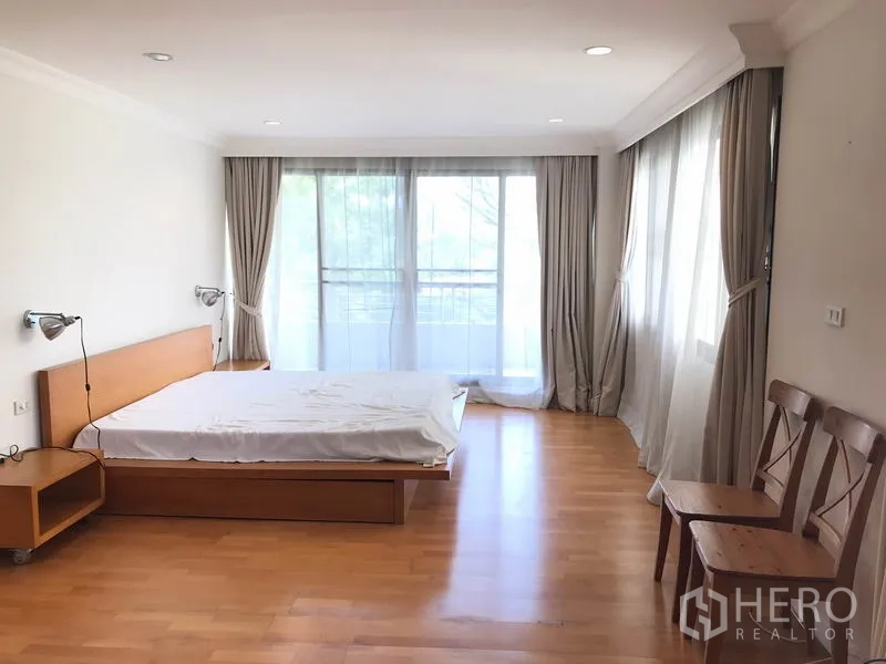 Condominium for rent in Sathon, Bangkok - Large master bedroom with big windows, sheer curtains and balcony access.