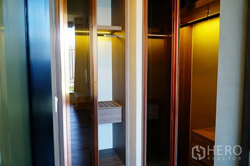 公寓 出租在Watthana, Bangkok - 带灯步入式衣柜，玻璃门与木质搁架。