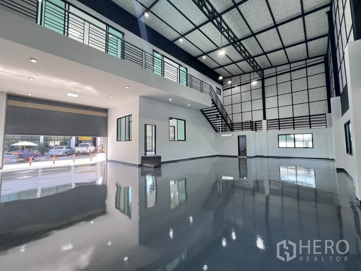 货栈 出售在Lam Luk Ka, Pathum Thani - 高挑仓库大厅，镜面环氧地坪、卷闸门与通往夹层的楼梯。