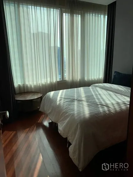 Condominium for rent in Bang Rak, Bangkok - Second bedroom with corner windows, sheer curtains, a double bed, and polished wooden floor.