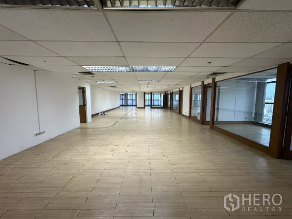 Office Space for rent in Watthana, Bangkok - Long rectangular workspace with suspended ceiling lights and glass partitions along the right wall.