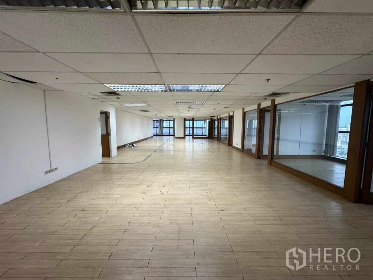 Office Space for rent in Watthana, Bangkok - Long rectangular workspace with suspended ceiling lights and glass partitions along the right wall.