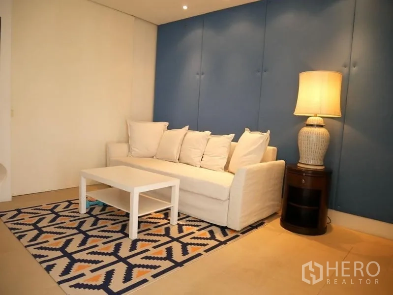 คอนโด ให้เช่าในKhlong Toei, Bangkok - มุมนั่งเล่นอบอุ่น โซฟาสีขาว พรมลาย และโคมไฟตั้งพื้น