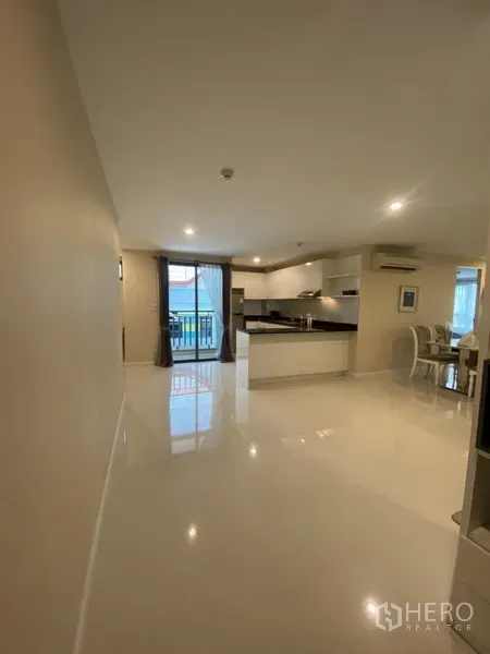 Condominium for rent in Watthana, Bangkok - Open-plan living and kitchen area with glossy floors and balcony access through large glass doors.