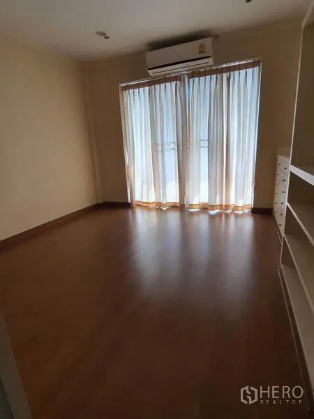 ทาวน์เฮาส์ ให้เช่าในHuai Khwang, Bangkok - ห้องนอนพื้นไม้ ประตูกระจกเปิดสู่ระเบียง พร้อมเครื่องปรับอากาศ