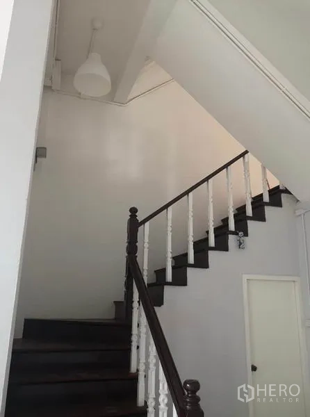 联排别墅 出租或出售在Din Daeng, Bangkok - 室内楼梯，深色木踏步与白色栏杆，高挑天花板。