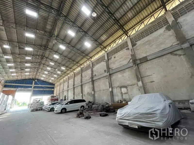Warehouse for rent in Phra Samut Chedi, Samut Prakan - Large column-free warehouse bay with bright roof panels and parking area.