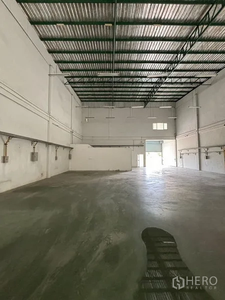 Warehouse for rent in Phra Samut Chedi, Samut Prakan - Spacious warehouse hall with high steel roof, concrete floor and rear loading door.