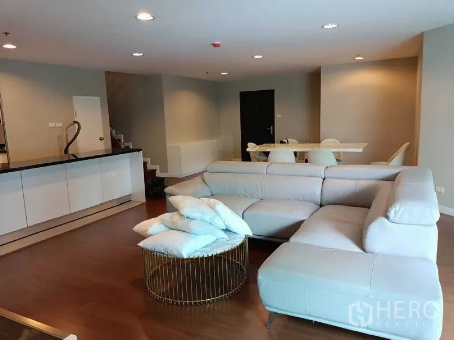 Condominium for rent or sale in Huai Khwang, Bangkok - Open-plan lounge view with sectional sofa, breakfast bar and wood floors.