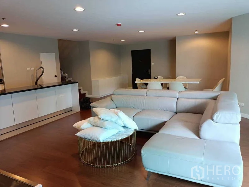 Condominium for rent or sale in Huai Khwang, Bangkok - Open-plan lounge view with sectional sofa, breakfast bar and wood floors.