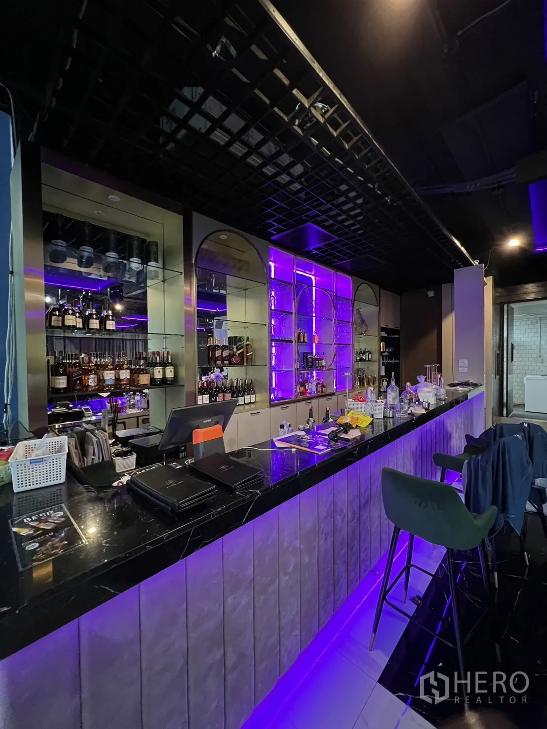 พื้นที่ขายปลีก ให้เช่า - เคาน์เตอร์บาร์หินอ่อนสีดำ พร้อมชั้นวางหลังบาร์ไฟ LED สีม่วง