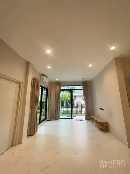 บ้าน ขายในBang Kruai, Nonthaburi - โถงนั่งเล่นชั้นล่าง ประตูกระจกบานเลื่อนออกสู่สวน ฝ้าดาวน์ไลท์ และพื้นกระเบื้อง