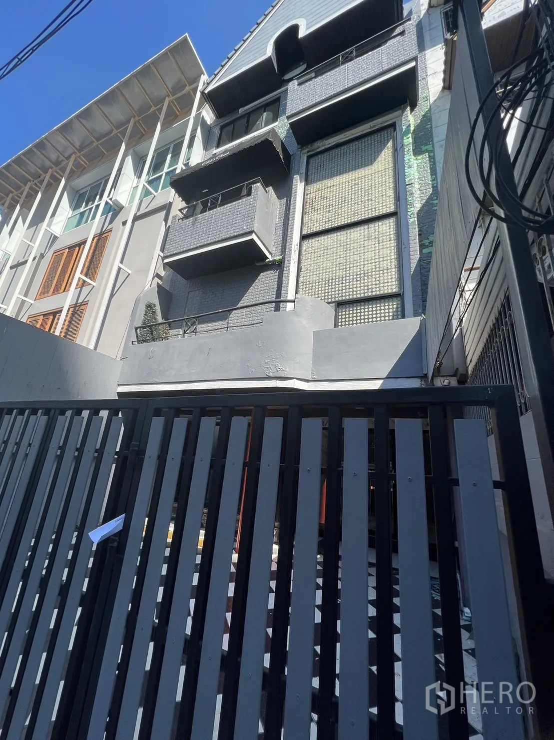 Home Office for rent in Watthana, Bangkok - Street view of gated townhome-style building with stacked balconies and tall facade.
