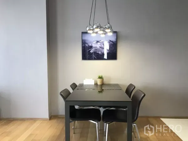 Condominium for rent in Watthana, Bangkok - Modern dining area with a four-seat black table beneath a cluster pendant light.