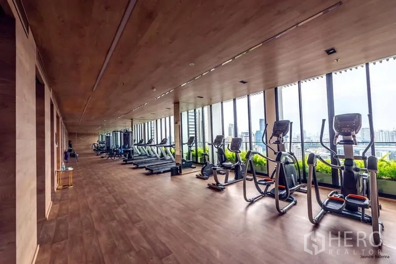 Condominium for rent in Watthana, Bangkok - Fully equipped fitness center with treadmills and ellipticals facing skyline windows.