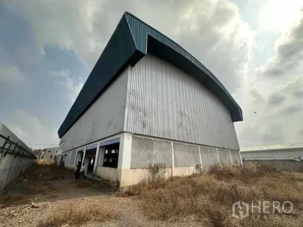 工厂 出租在Pak Kret, Nonthaburi - 仓库侧立面，波纹金属墙体与碎石维护通道。