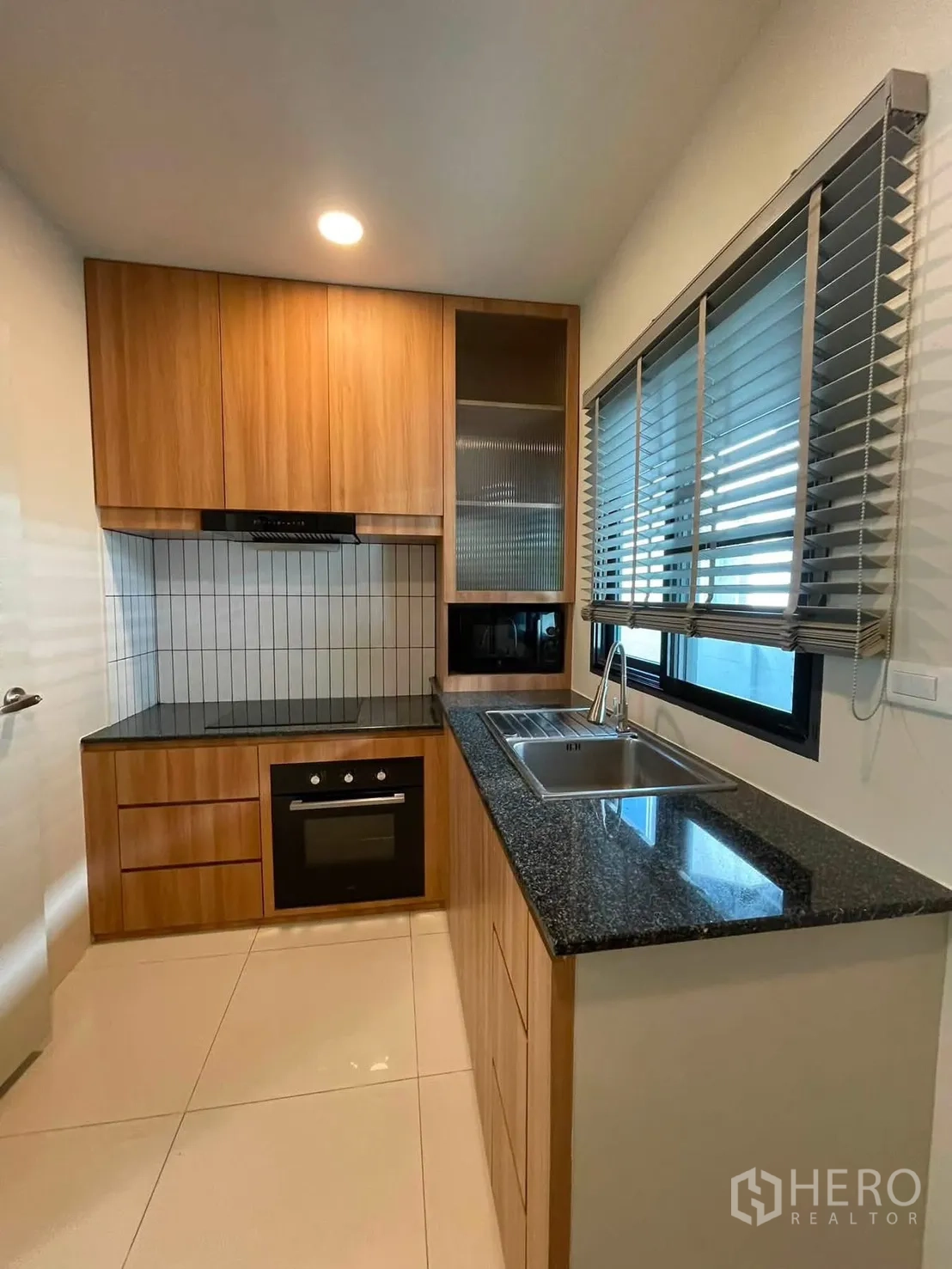 独栋房屋 for rent in Bang Phli, Samut Prakan - 紧凑厨房配花岗岩台面、木质橱柜、嵌入式烤箱、电灶、抽油烟机与水槽百叶窗。