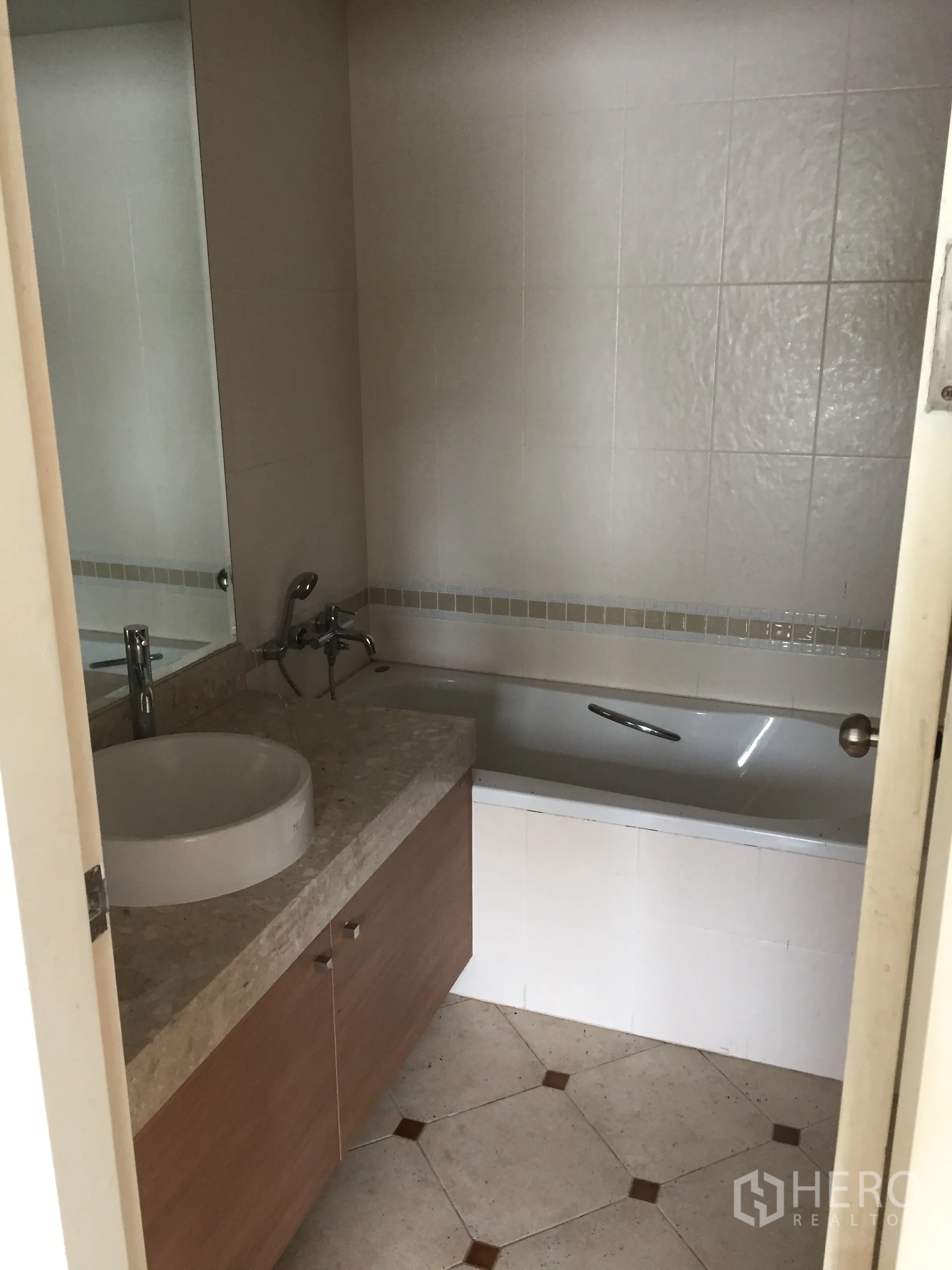 Condominium for sale in Khlong Toei, Bangkok - Bathroom with full bathtub, stone vanity, round basin and large wall mirror.