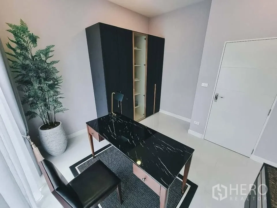 Detached House for rent or sale in Bang Phli, Samut Prakan - Home office with black marble-top desk, cabinet, and large plant by full-height window.