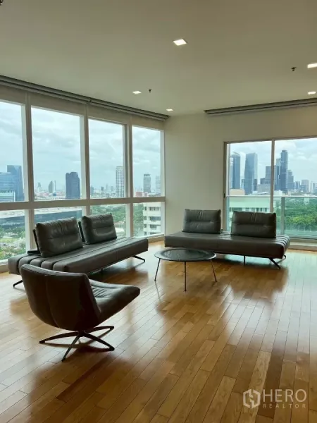 公寓 出租在Khlong Toei, Bangkok - 大窗旁的会客区，享受天际线与绿地景观，木地板与射灯天花。