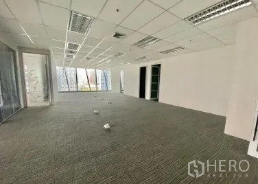 Office Space for rent - Open-plan office with carpet tiles, drop ceiling lighting and corner windows providing natural light.