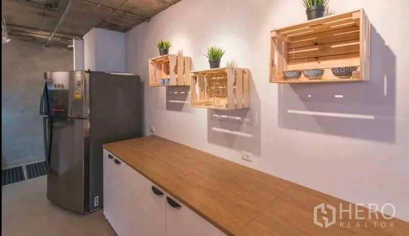 Condominium for rent in Watthana, Bangkok - Compact pantry with wood countertop, crate wall shelves and a stainless steel refrigerator.