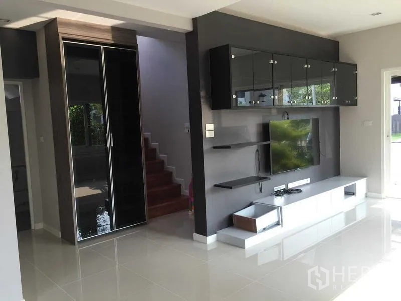 Townhouse for sale in Bang Khae, Bangkok - Sleek living space with glossy built-in TV cabinet opposite the staircase.