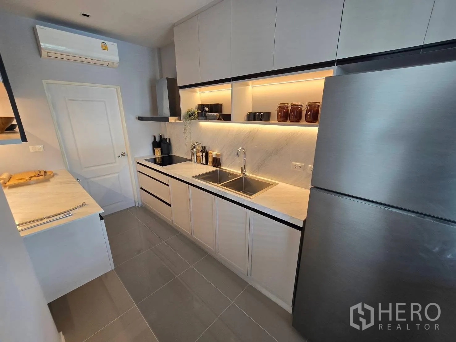 Semi-detached House for rent in Bang Phli, Samut Prakan - Galley kitchen with white cabinetry, double sink, cooktop and refrigerator.