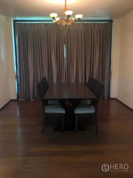 Townhouse for rent in Khlong Toei, Bangkok - Dining room with a dark wooden table, six chairs, chandelier lighting, and floor‑to‑ceiling curtains on hardwood floors.