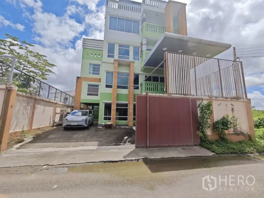 Office Space for rent in Prawet, Bangkok - Four-storey office building in Prawet with gated entrance and driveway parking.