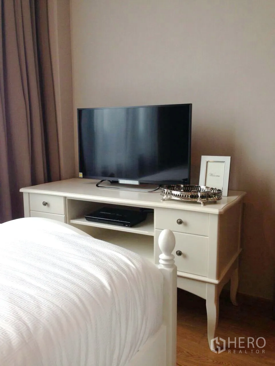 公寓 出租在Khlong Toei, Bangkok - 卧室内的白色电视柜摆放平面电视与硬木地板。