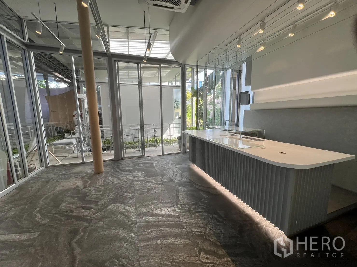 零售空间 出租在Khlong Toei, Bangkok - 带灯长展示吧台，旁为落地玻璃与绿植景观的现代零售空间。