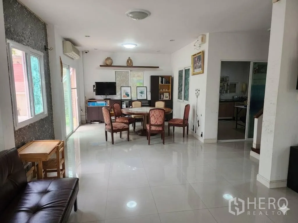 Detached House for rent in Lam Luk Ka, Pathum Thani - Bright living and dining area with round table, TV console, large windows, and tiled floors.