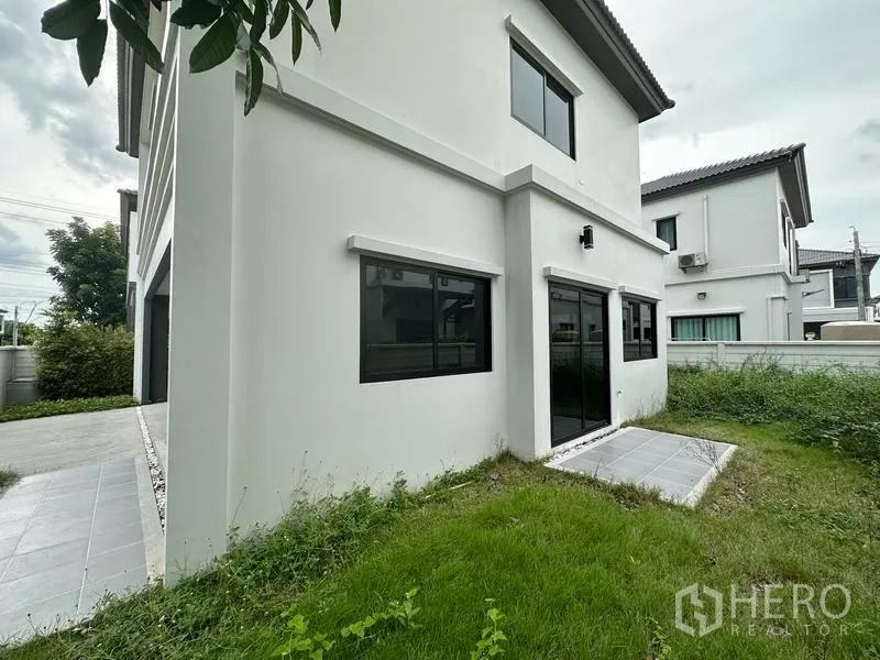 Detached House for sale in Khlong Sam Wa, Bangkok - Rear garden with lawn, sliding glass doors and boundary fence