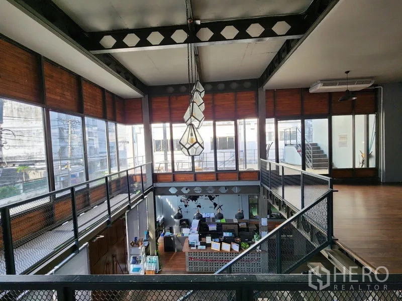 Home Office for rent in Mueang Nonthaburi, Nonthaburi - Mezzanine walkway overlooking the double-height lobby with geometric pendant lights and large windows.