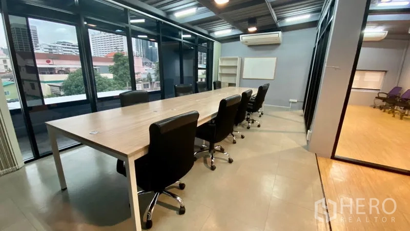 办公空间 出租在Sathon, Bangkok - 会议室配长桌、黑色座椅、大窗与壁挂式空调。