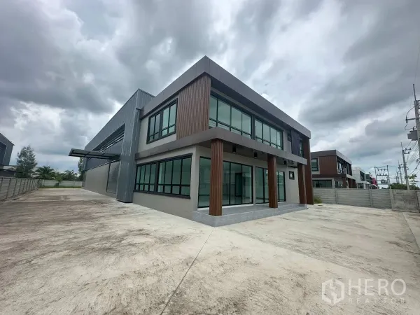 Factory for rent in Bang Len, Nakhon Pathom - Angled view of the factory showing the glass office facade and attached steel-clad warehouse.