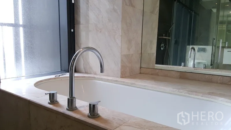 Condominium for rent in Sathon, Bangkok - Marble bathroom featuring a built-in soaking bathtub and wide mirror.